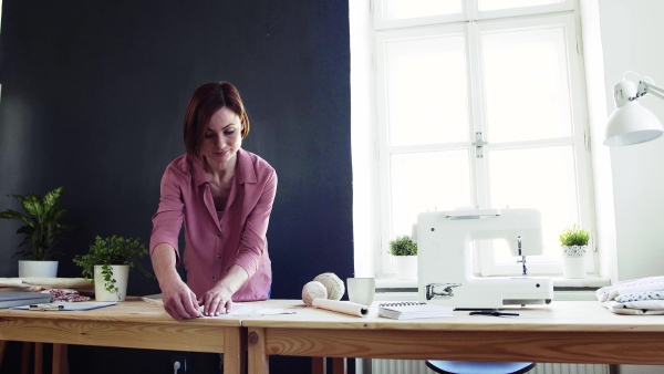 Young creative woman in a studio, working. A startup of small tailoring business.