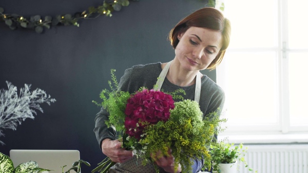 A young creative woman arranging flowers in a flower shop. A startup of florist business.