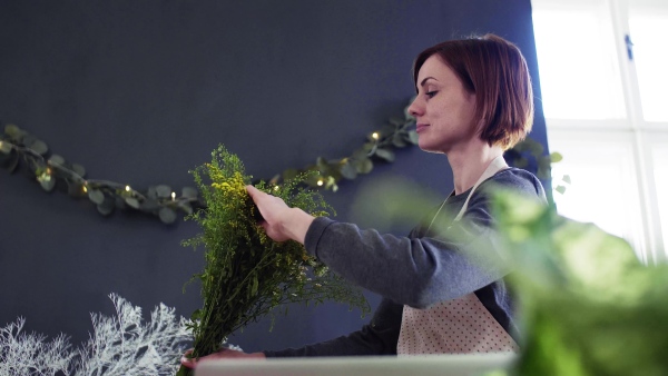 A young creative woman arranging flowers in a flower shop. A startup of florist business.