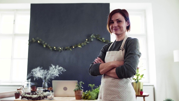 Portrait of young creative woman standing in a flower shop. A startup of florist business.