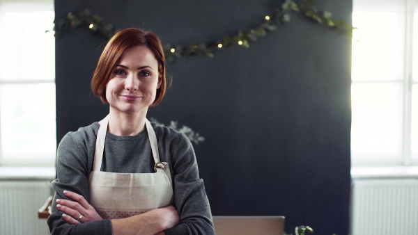 Portrait of young creative woman standing in a flower shop. A startup of florist business.