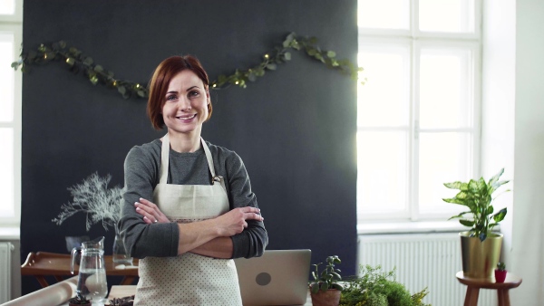 Portrait of young creative woman standing in a flower shop. A startup of florist business.