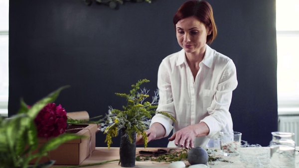 A young creative woman arranging flowers in a flower shop. A startup of florist business.