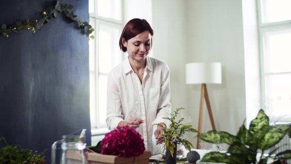 A young creative woman arranging flowers in a flower shop. A startup of florist business.