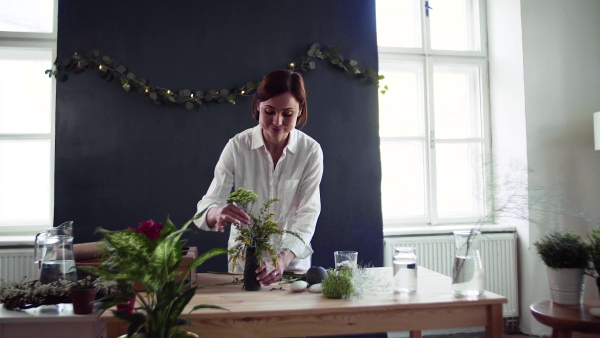 A young creative woman arranging flowers in a flower shop. A startup of florist business.