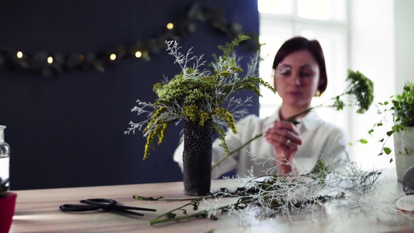 A young creative woman arranging flowers in a flower shop. A startup of florist business.