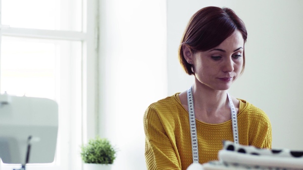 Young creative woman working in a studio, startup of small tailoring business.