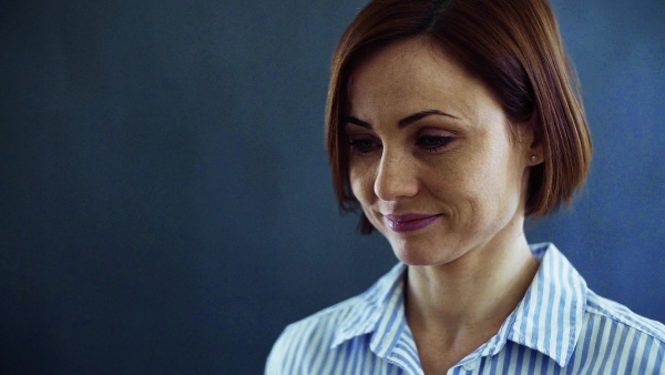 A close-up portrait of young cheerful woman standing indoors. Slow motion.