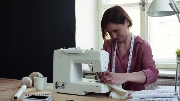 Young creative woman in a studio, working. A startup of small tailoring business. Slow motion.