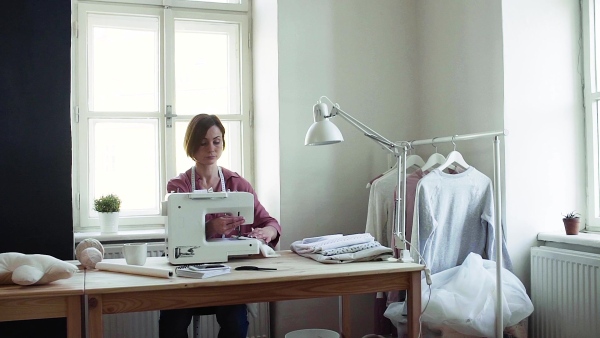 Young creative woman in a studio, working. A startup of small tailoring business. Slow motion.