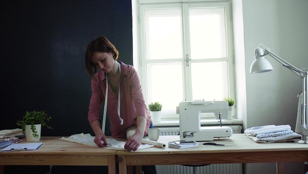 Young creative woman in a studio, working. A startup of small tailoring business. Slow motion.