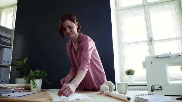 Young creative woman in a studio, working. A startup of small tailoring business. Slow motion.