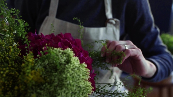 A midsection of young creative woman arranging flowers in a flower shop. A startup of florist business. Slow motion.