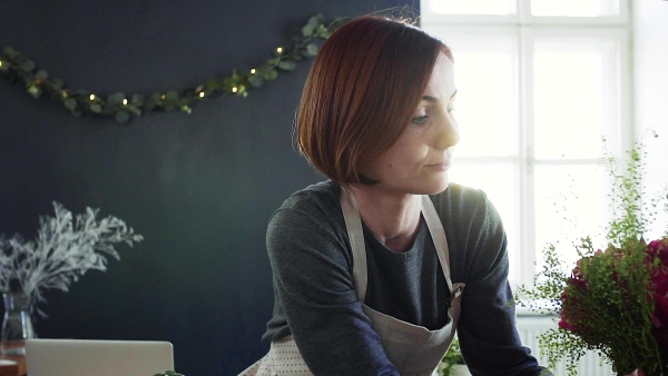 A young creative woman arranging flowers in a flower shop. A startup of florist business. Slow motion.