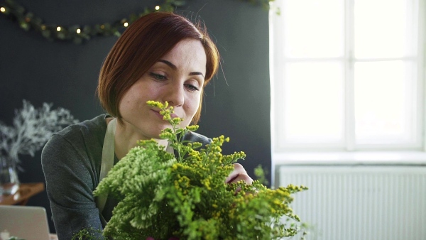 A young creative woman arranging flowers in a flower shop. A startup of florist business. Slow motion.