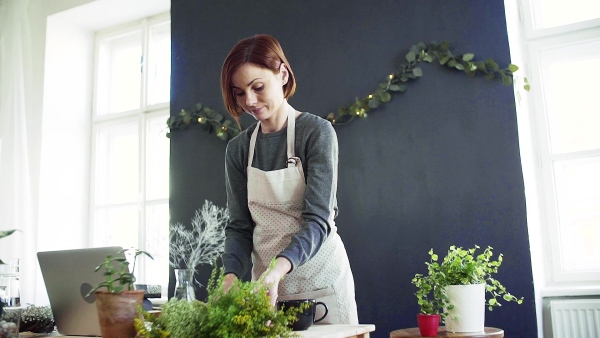 A young creative woman arranging flowers in a flower shop. A startup of florist business. Slow motion.