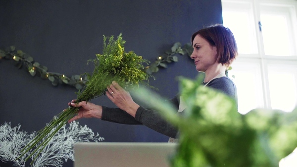 A young creative woman arranging flowers in a flower shop. A startup of florist business. Slow motion.