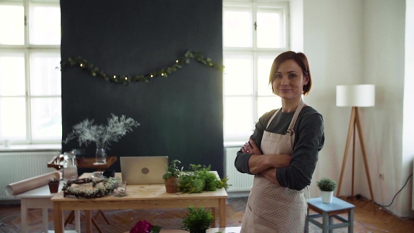 Portrait of young creative woman standing in a flower shop. A startup of florist business. Slow motion.