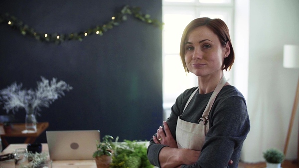 Portrait of young creative woman standing in a flower shop. A startup of florist business. Slow motion.