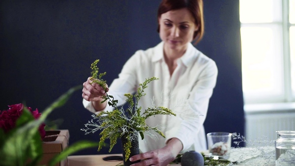 A young creative woman arranging flowers in a flower shop. A startup of florist business. Slow motion.