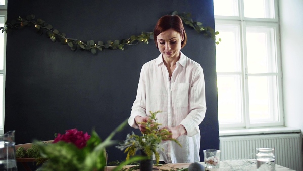 A young creative woman arranging flowers in a flower shop. A startup of florist business. Slow motion.