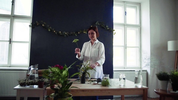 A young creative woman arranging flowers in a flower shop. A startup of florist business. Slow motion.