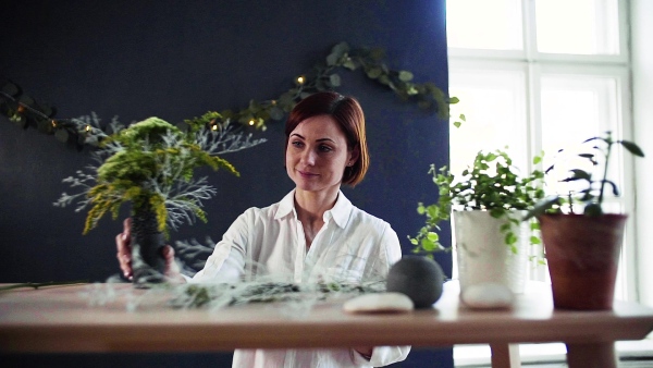 A young creative woman arranging flowers in a flower shop. A startup of florist business. Slow motion.