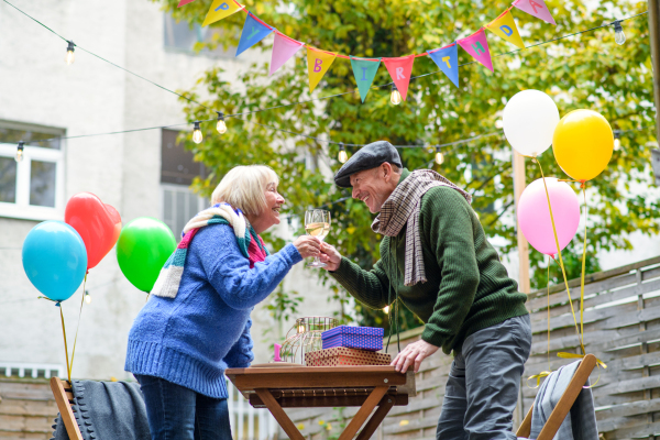 Portrait of happy senior couple with wine in outdoor cafe in city, celebrating birthday.