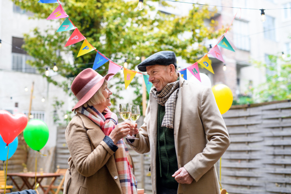 Portrait of happy senior couple with wine in outdoor cafe in city, celebrating birthday.