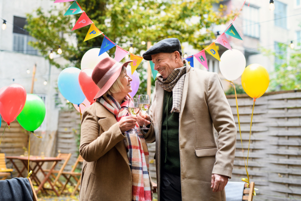 Portrait of happy senior couple with wine in outdoor cafe in city, celebrating birthday.