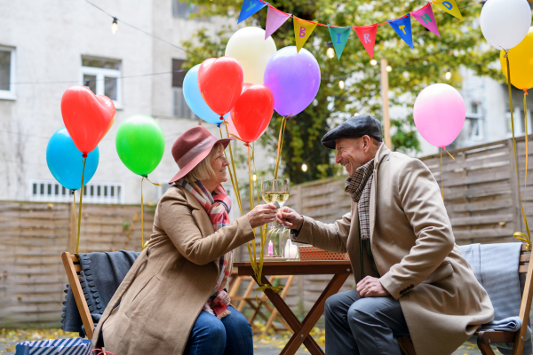 Portrait of happy senior couple with wine in outdoor cafe in city, celebrating birthday.