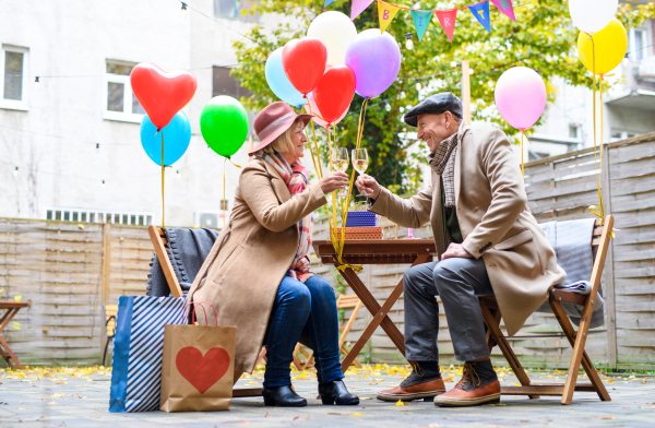 Portrait of happy senior couple with wine in outdoor cafe in city, celebrating birthday.