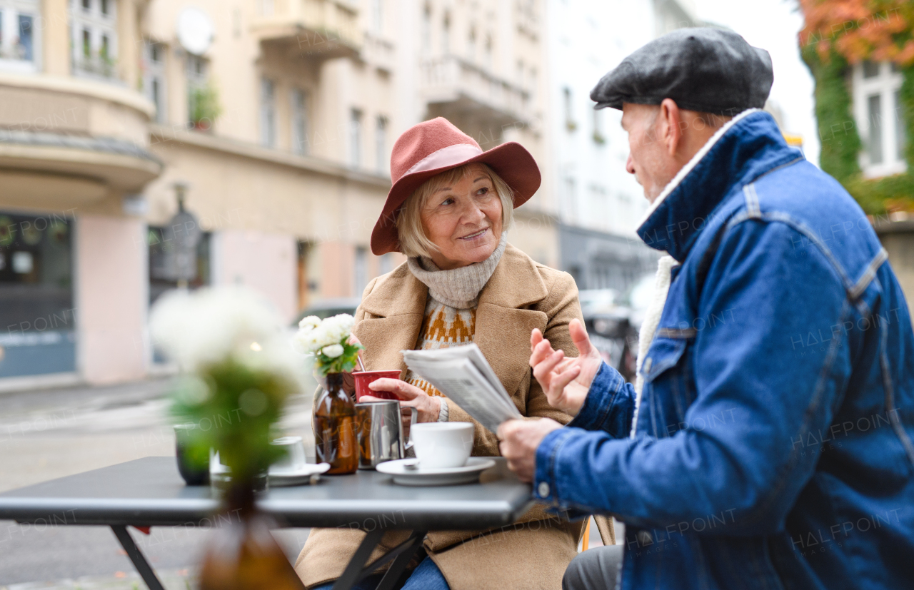 Happy senior people sitting in outdoor cafe in city, talking.