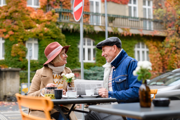 Happy senior people sitting in outdoor cafe in city, talking.