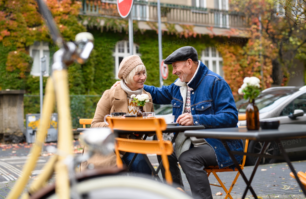 Happy senior people sitting in outdoor cafe in city, talking.