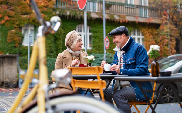 Happy senior people sitting in outdoor cafe in city, talking.