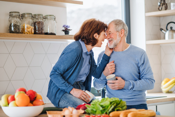 A portrait of happy senior couple in love indoors at home, laughing.