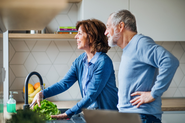 A portrait of happy senior couple indoors at home, cooking.