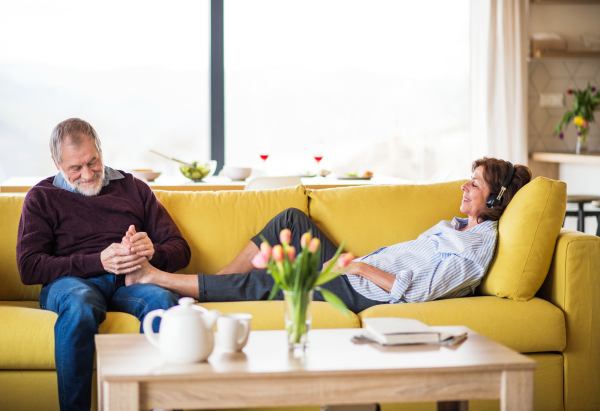 An affectionate senior couple in love sitting on sofa indoors at home, relaxing.