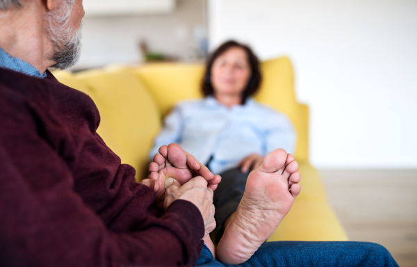 An affectionate senior couple in love sitting on sofa indoors at home, relaxing.