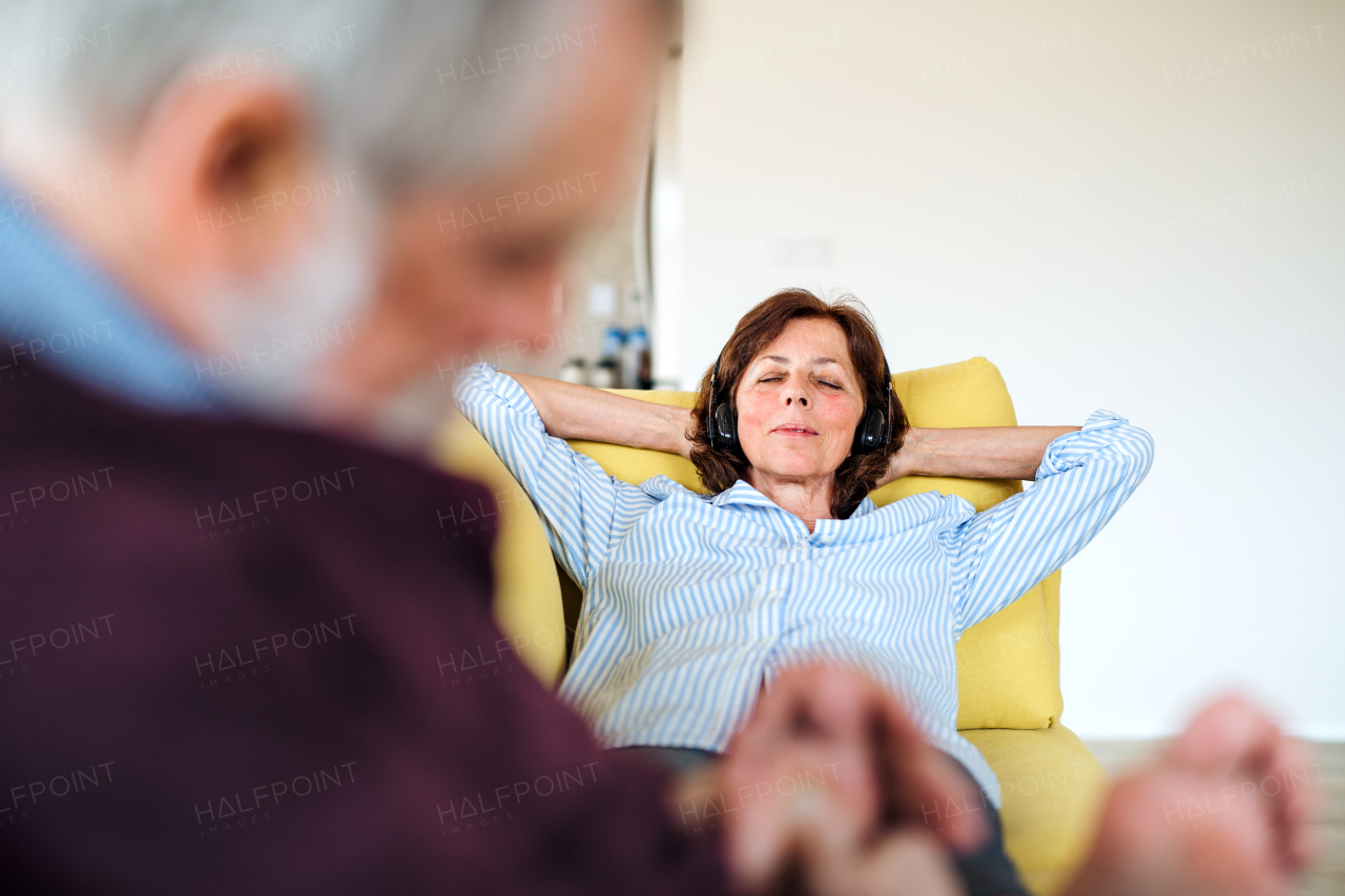 An affectionate senior couple in love sitting on sofa indoors at home, relaxing.