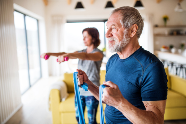 A happy senior couple indoors at home, doing exercise indoors.