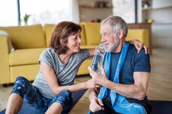 A happy senior couple indoors at home, doing exercise on the floor.