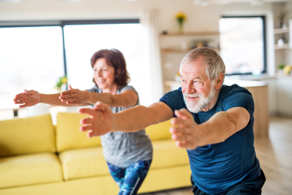 A happy senior couple indoors at home, doing exercise indoors.