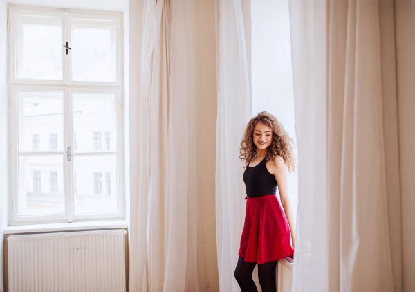 A portrait of young dance woman teacher indoors standing by window. Copy space.