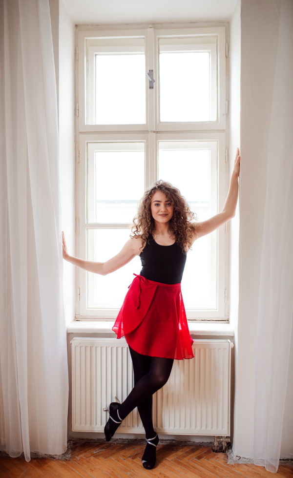 A portrait of young dance woman teacher indoors standing by window. Copy space.