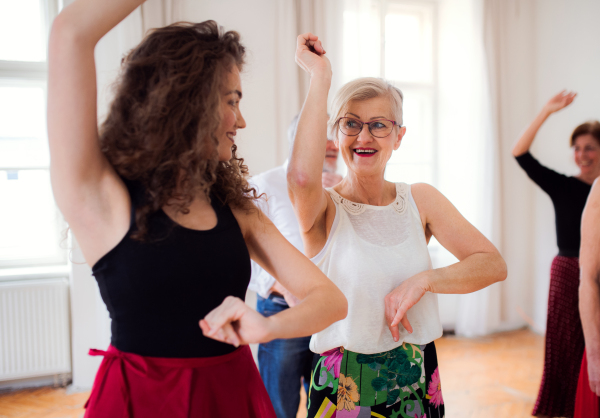 A group of senior people attending dancing class with dance teacher.