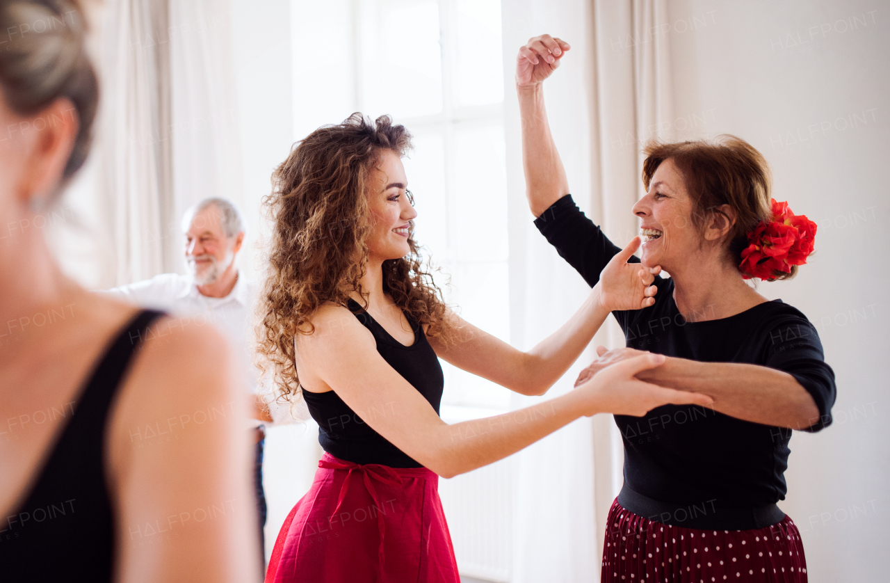 A group of senior people attending dancing class with dance teacher.