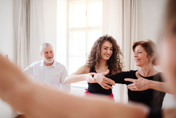 A group of senior people attending dancing class with dance teacher.