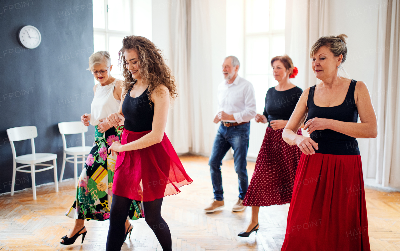 A group of senior people attending dancing class with dance teacher.